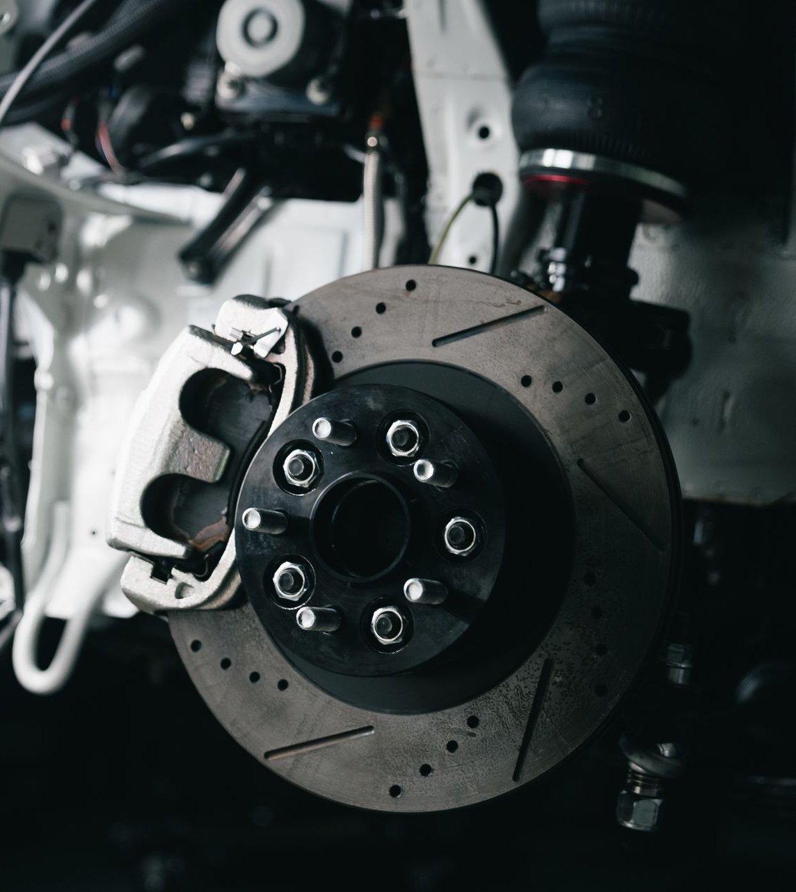 Close-up of a brake caliper clamped over a drilled and slotted rotor